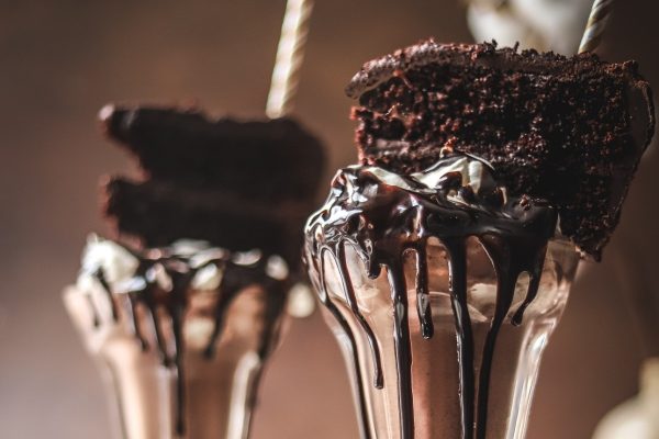 Indulge in creamy chocolate ice cream sundaes topped with fluffy whipped cream and sprinkled with delectable chocolate shavings.