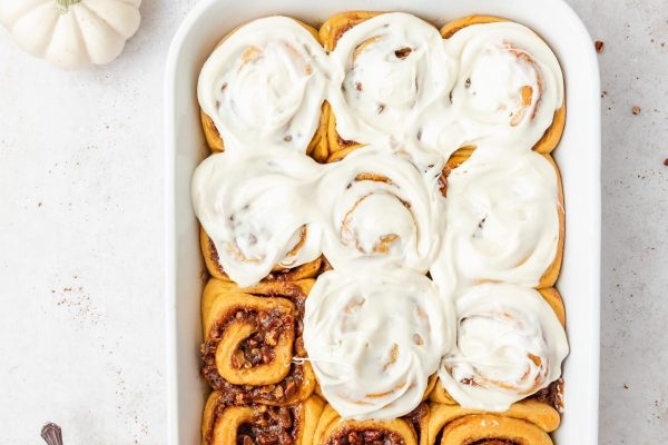 Pumpkin cinnamon rolls in a white baking dish filled with warm, gooey deliciousness.