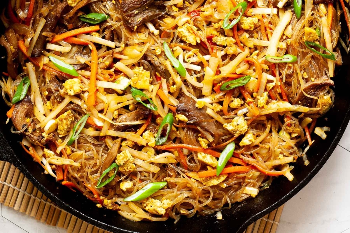 A skillet filled with noodles, meat and vegetables.