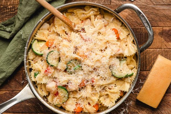 A delicious pasta dish made with pantry staples, filled with vegetables and presented on a charming wooden table.