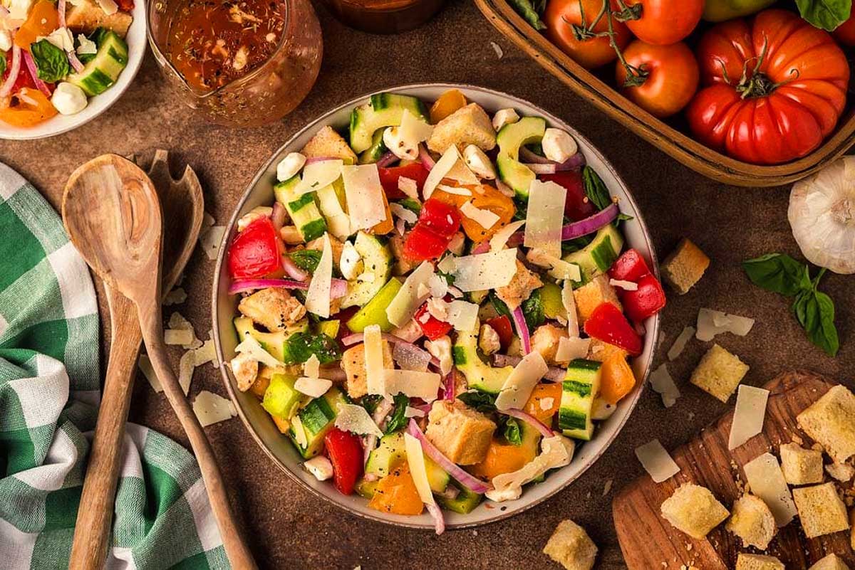 A bowl of salad with tomatoes, cucumbers and croutons.