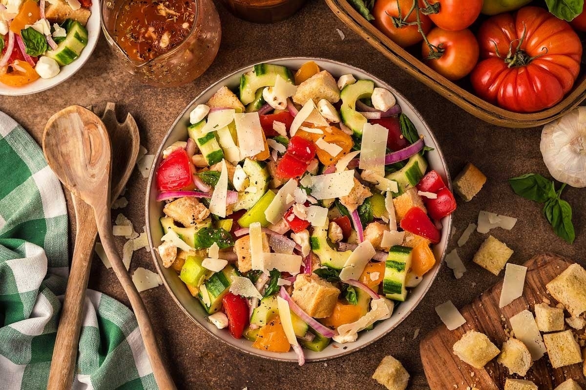 A bowl of salad with tomatoes, cucumbers and croutons.