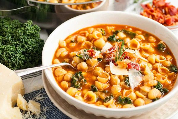 A bowl of chickpea and kale soup with a spoon.