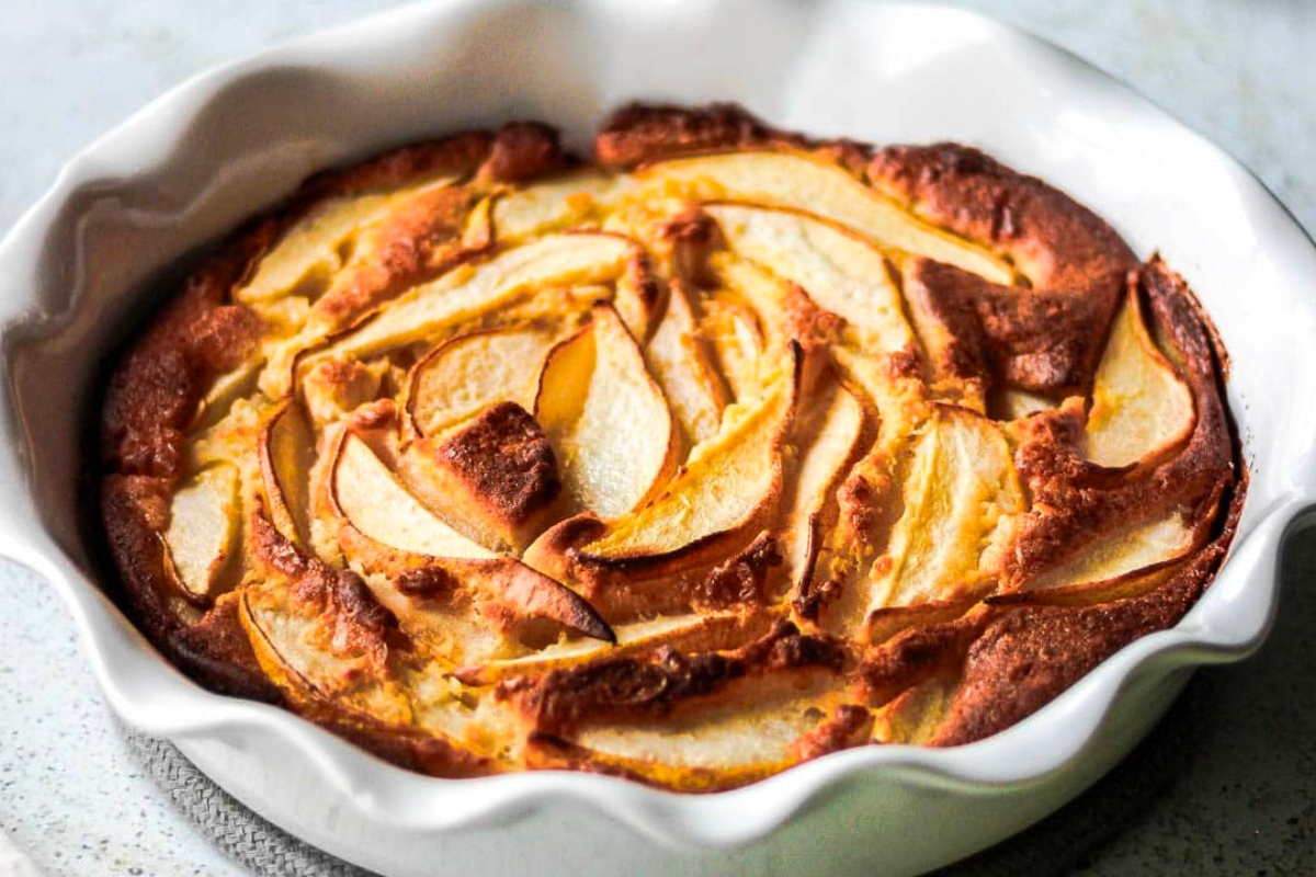 A country-style apple pie in a white dish on a table.