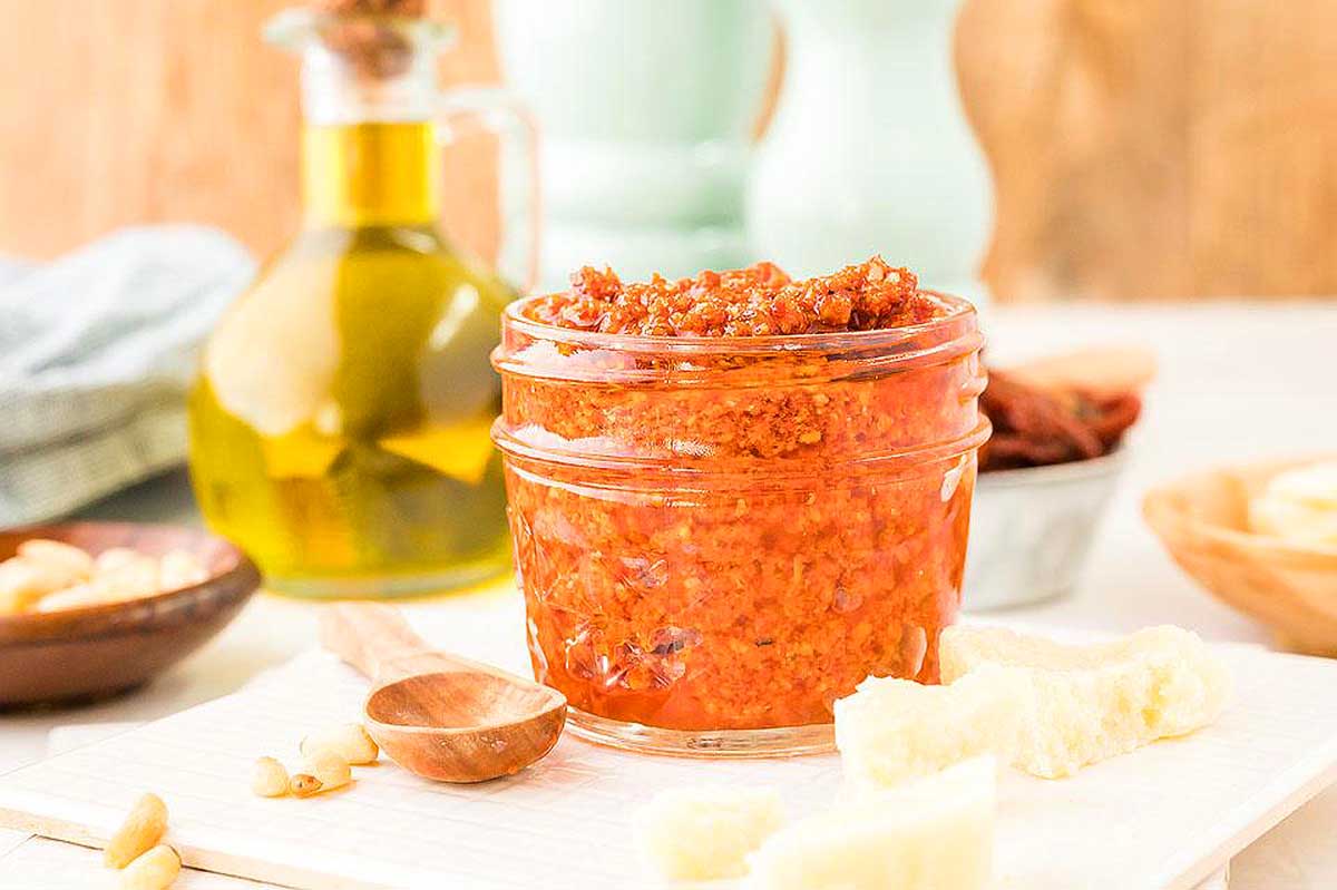 A jar of pesto on a white plate, perfect for adding flavor to your favorite recipes.