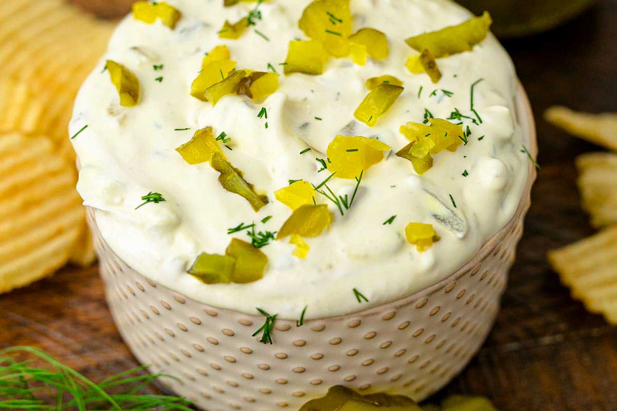 A bowl of dip with chips and dill.