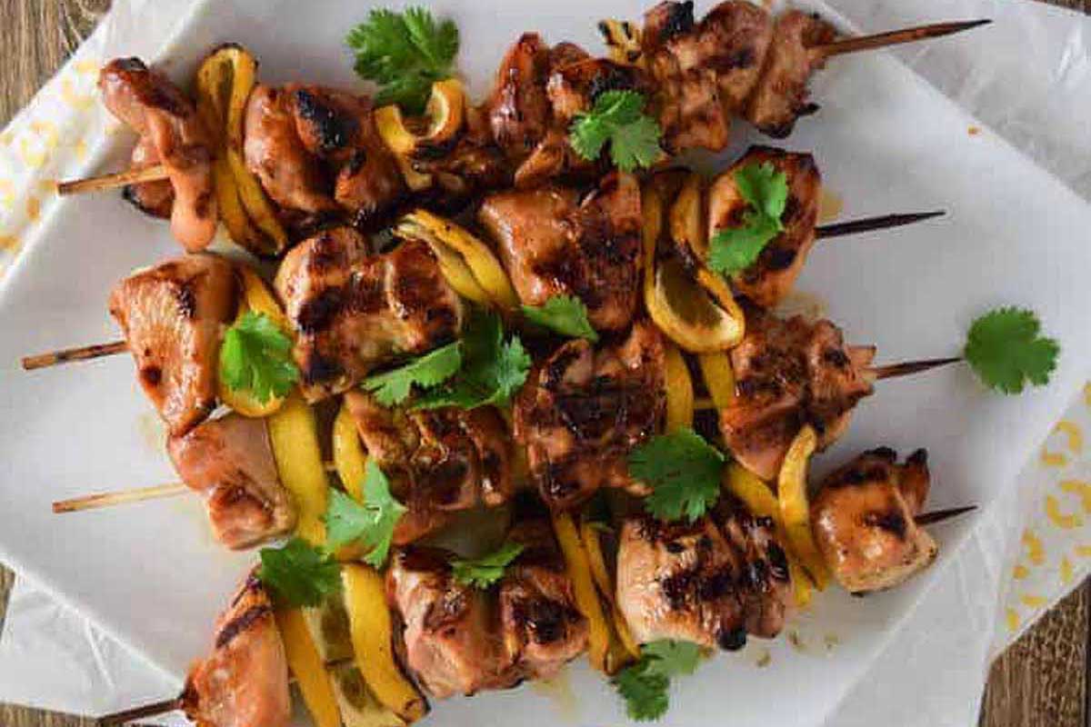 Grilled chicken on skewers served on a white plate.