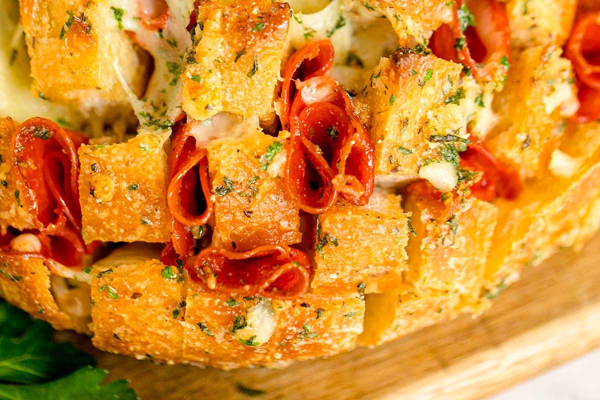 A bread with pepperoni and cheese on a cutting board.