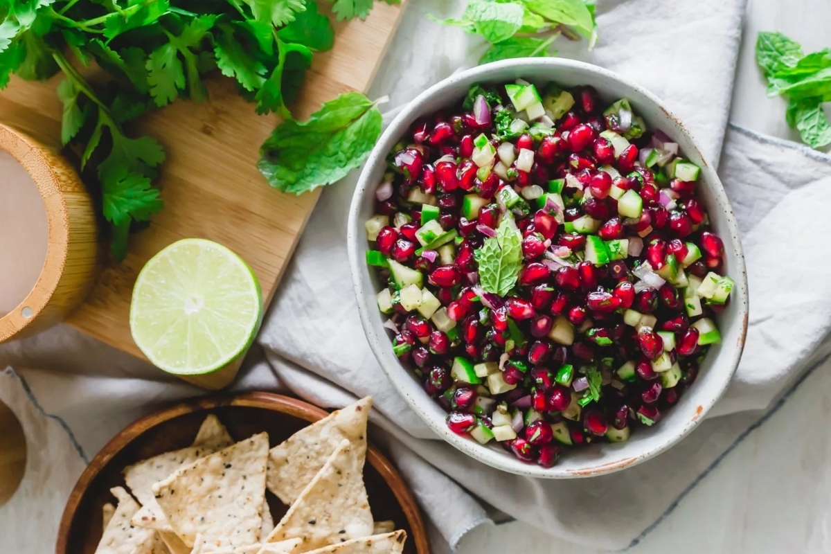 A bowl of pomegranate salsa with lime and tortilla chips.