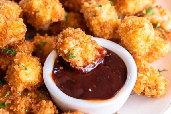 Fried chicken nuggets with dipping sauce on a plate.