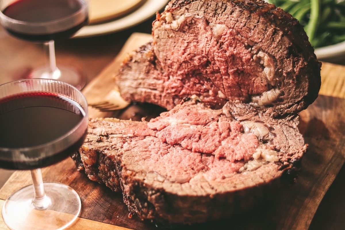 Two glasses of red wine on a wooden cutting board, perfect for complementing your Thanksgiving mains.