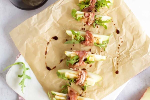 A plate of apple and arugula appetizers with a bottle of wine.