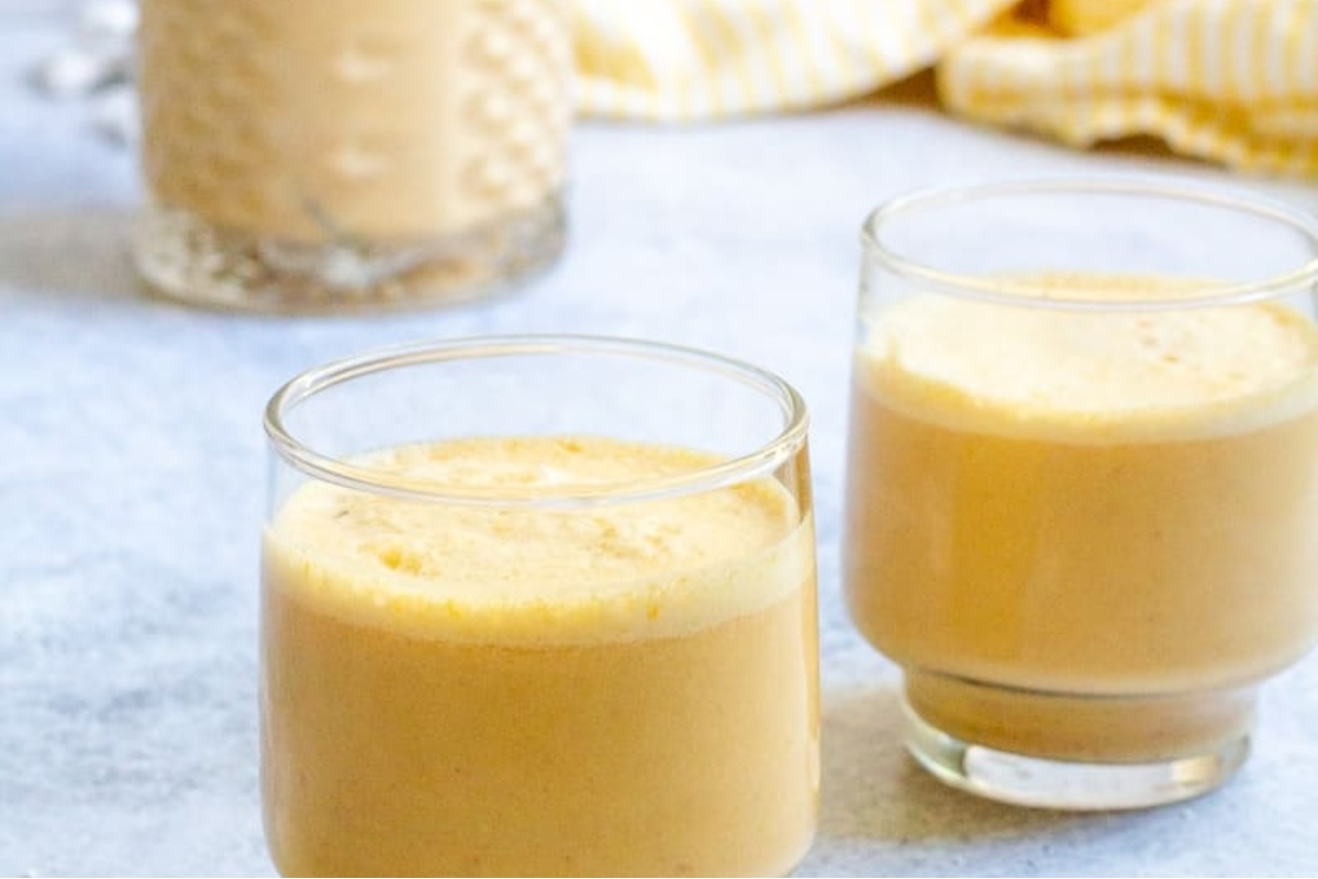 Two glasses of banana smoothie on a table with recipes.