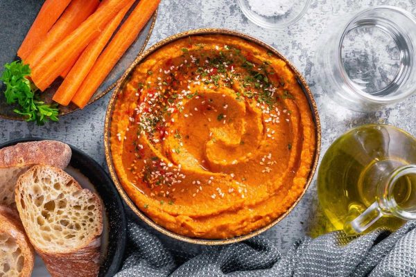 A budget-friendly bowl of hummus with carrots and bread, perfect for a potluck gathering or Thanksgiving feast.