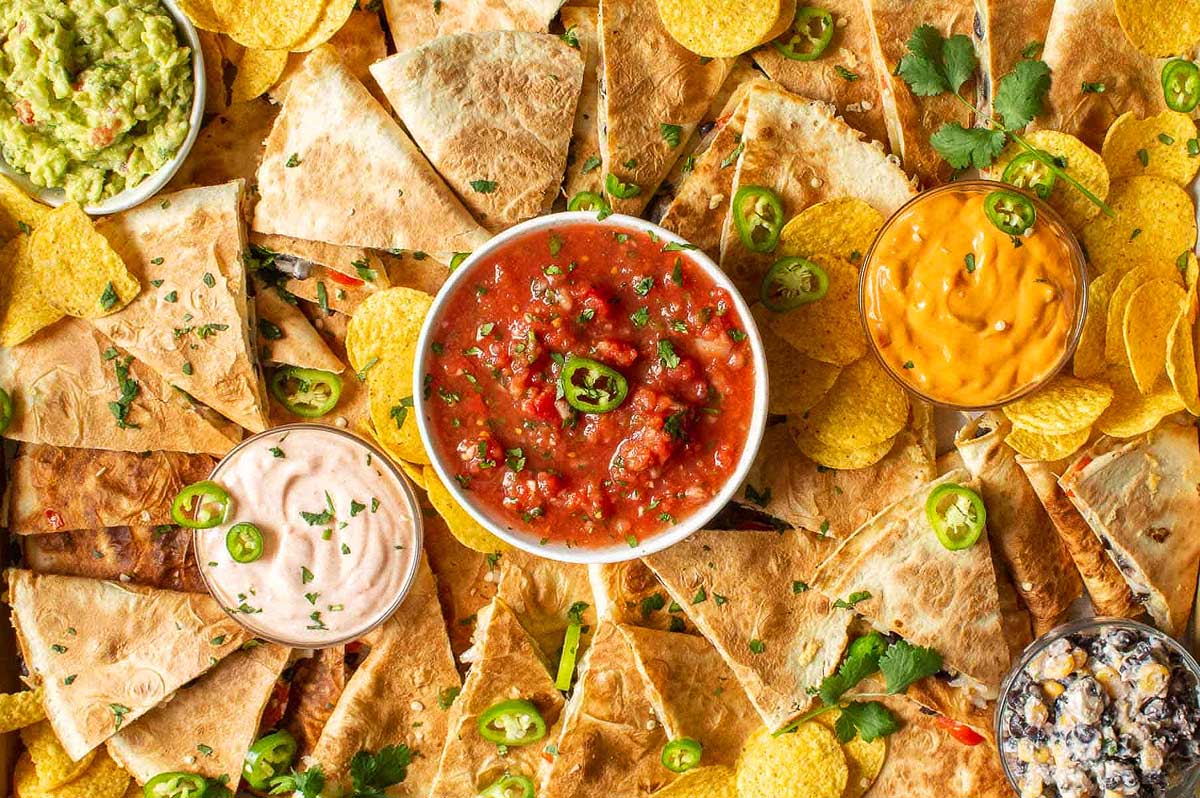 A plate of nachos, chips, salsa and guacamole.