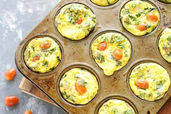 A muffin tin filled with egg and spinach quiche muffins.