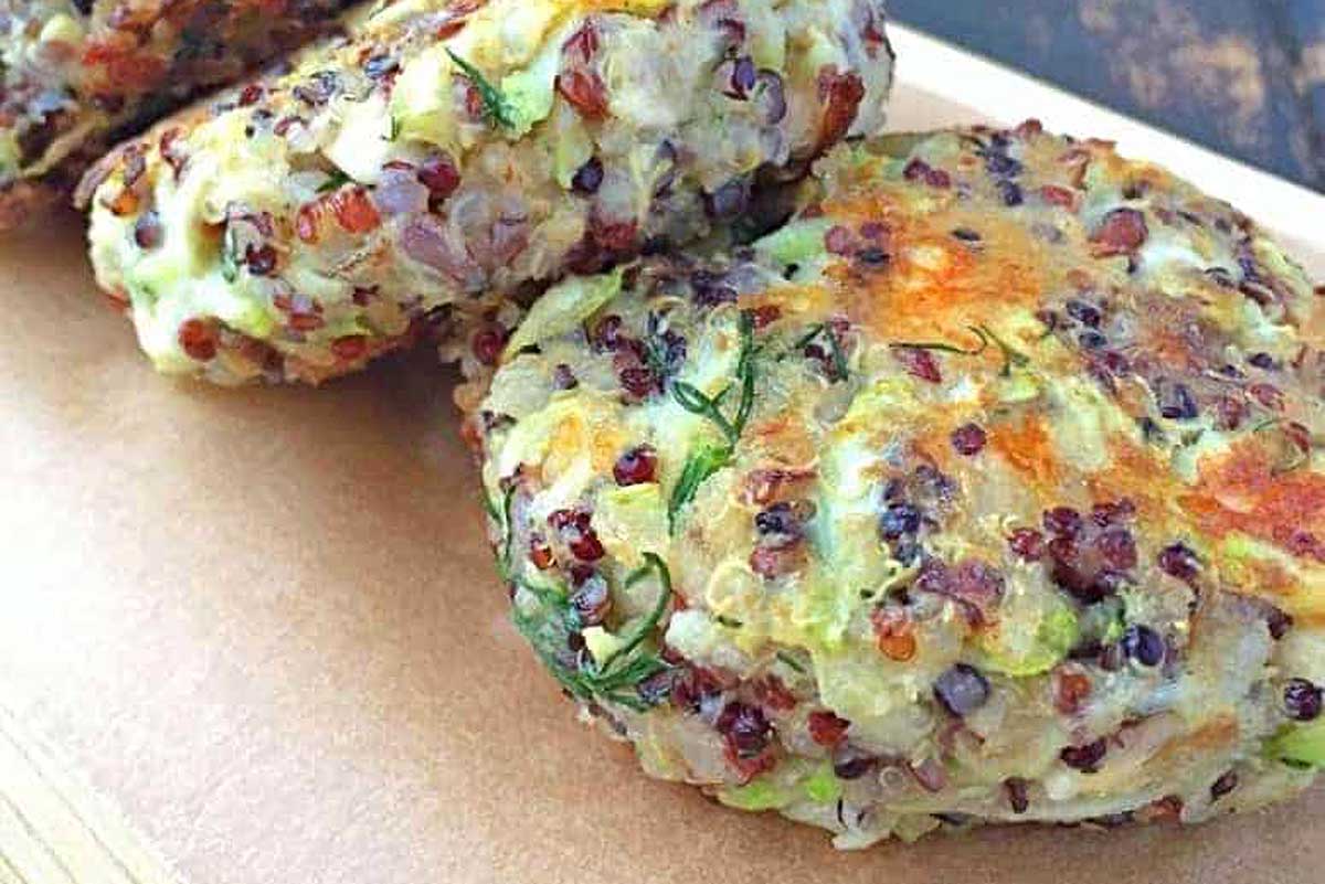 Zucchini-stuffed quinoa burgers on a wooden cutting board.