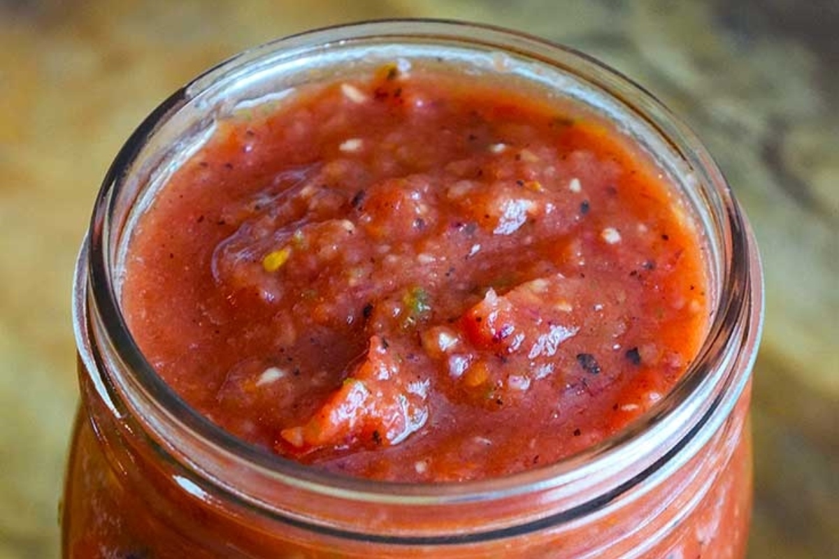 Tomato sauce in a jar on a wooden table.