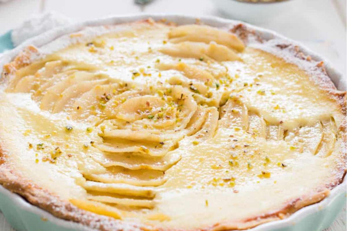 An Italian dessert tart with apples and pistachios on top.