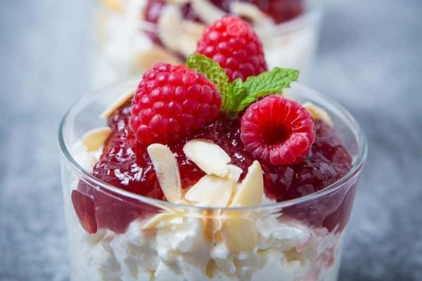 A Christmas dessert with raspberries and almonds in a glass.