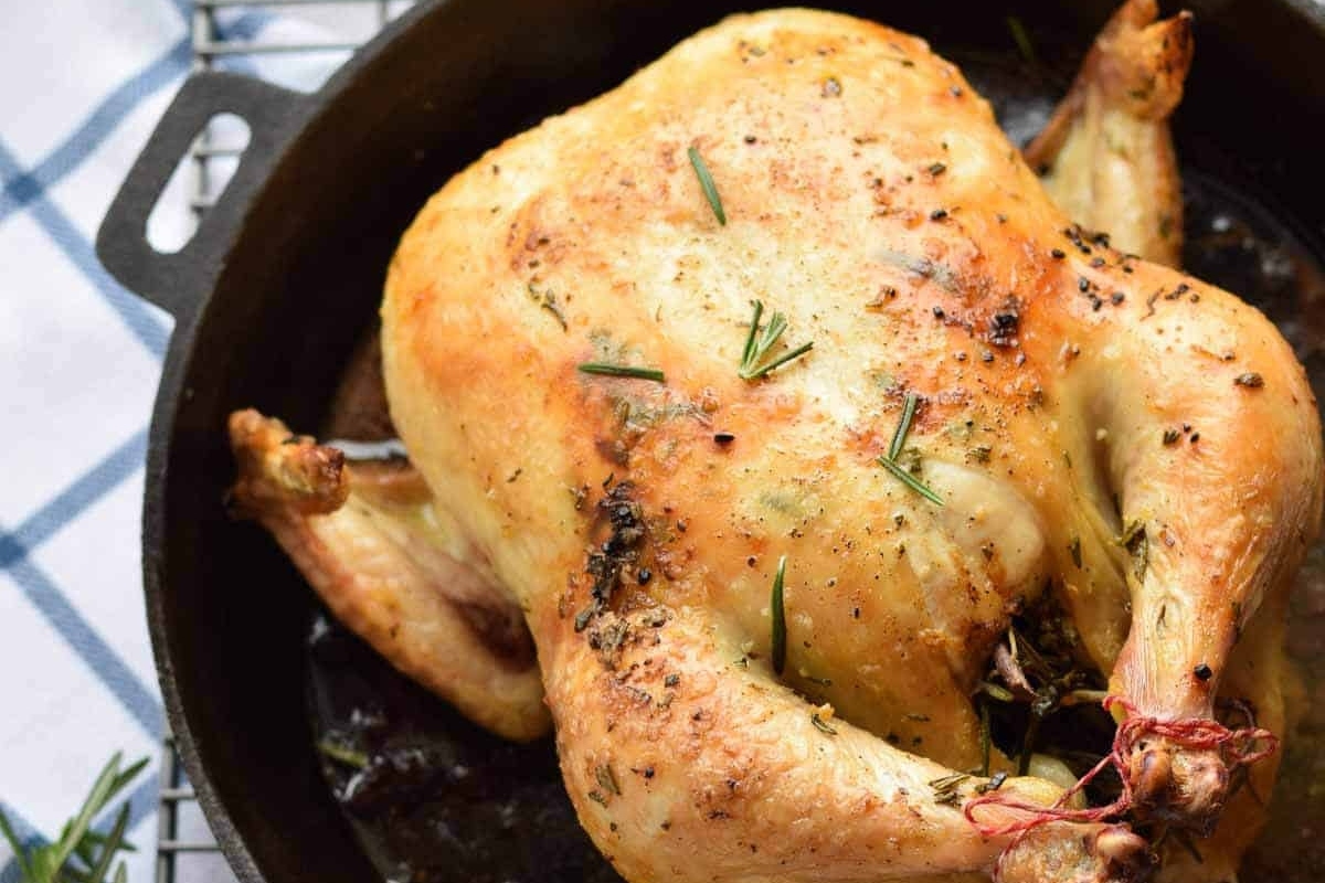 A Thanksgiving main dish featuring a succulent roasted chicken cooked in a cast iron skillet.