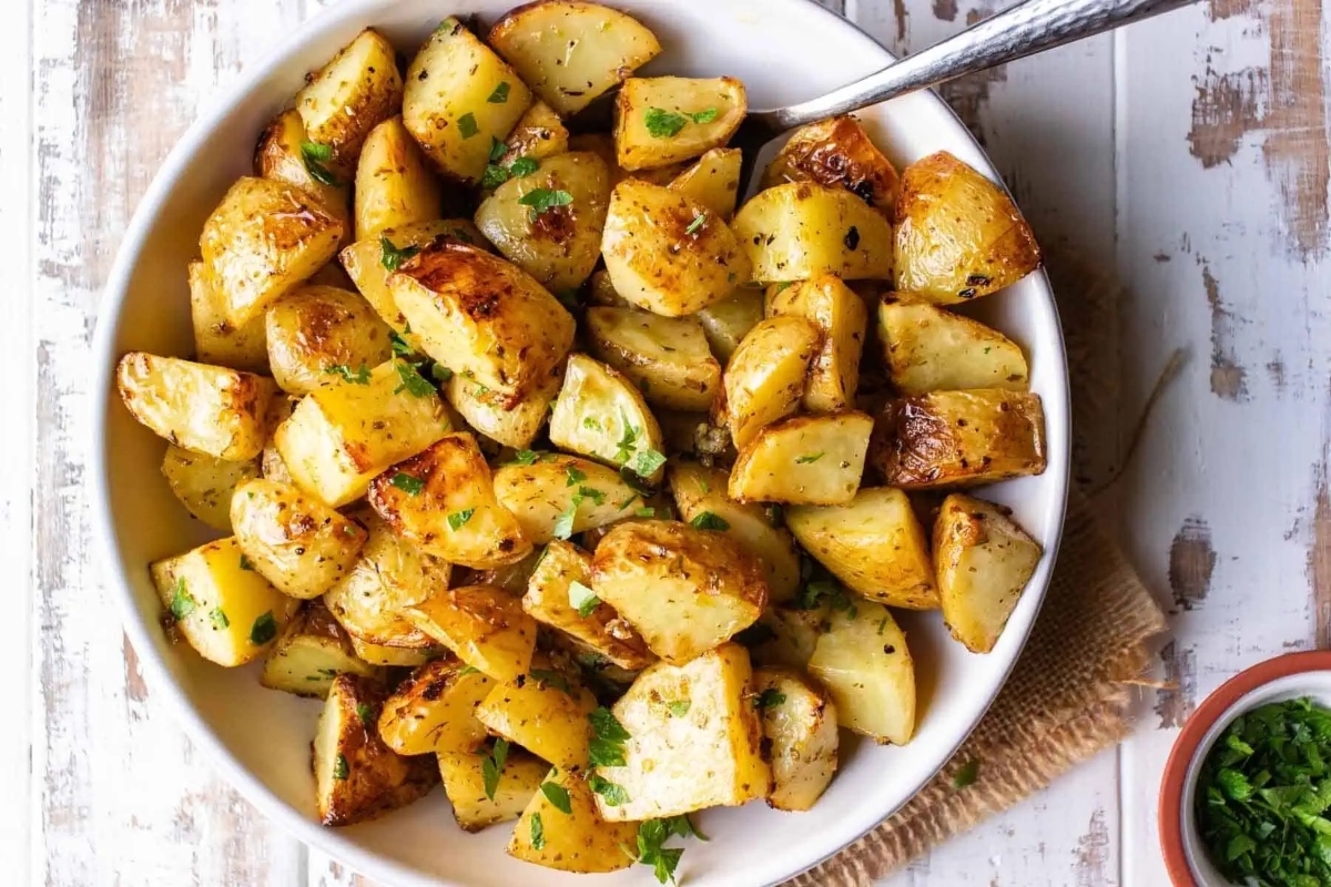 Thanksgiving roasted potatoes in a white bowl on a wooden table.