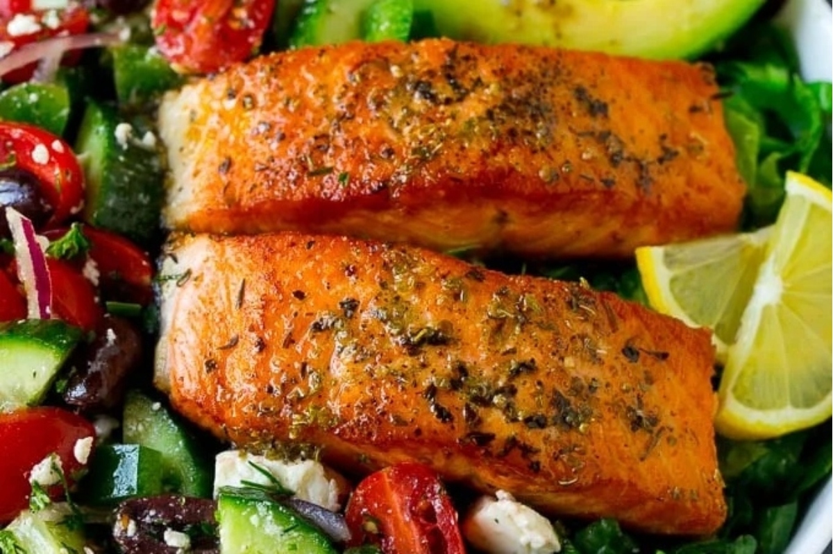 A dinner bowl of salmon salad with tomatoes, cucumbers, and olives.