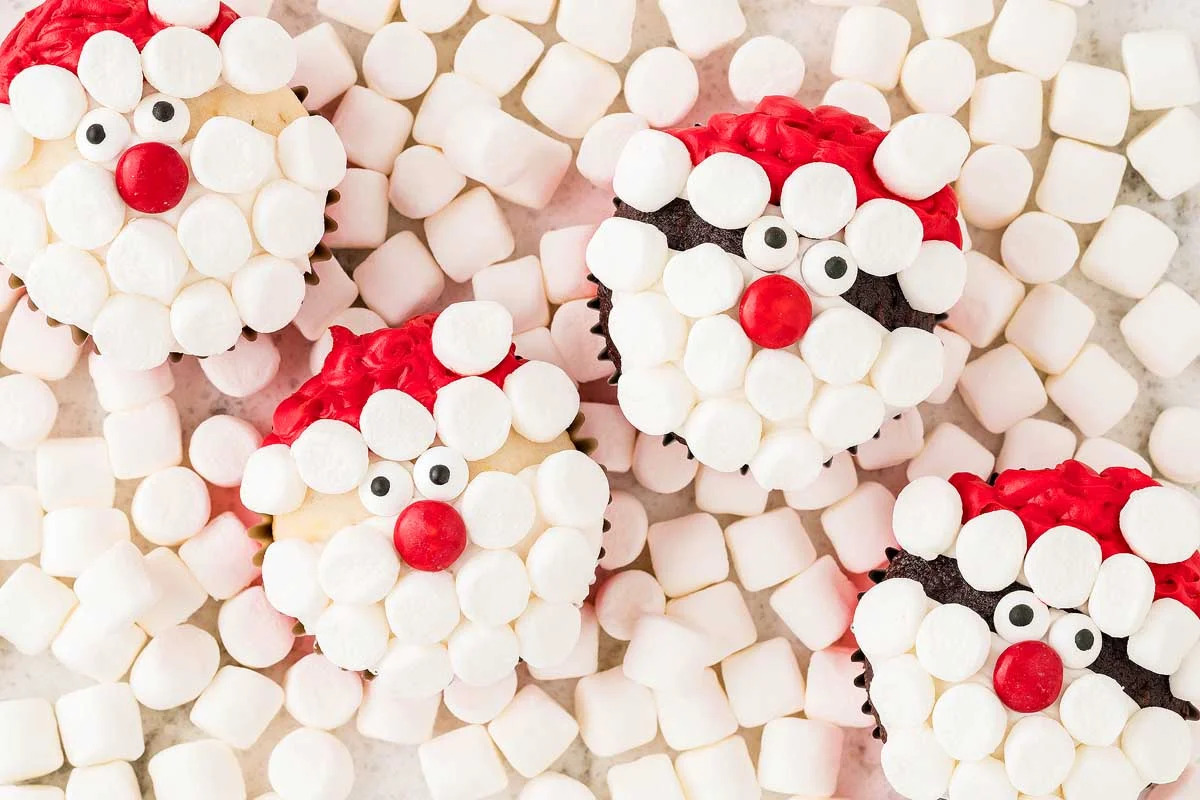 These cute Christmas cupcakes are adorned with marshmallows and adorable Santa Claus faces.