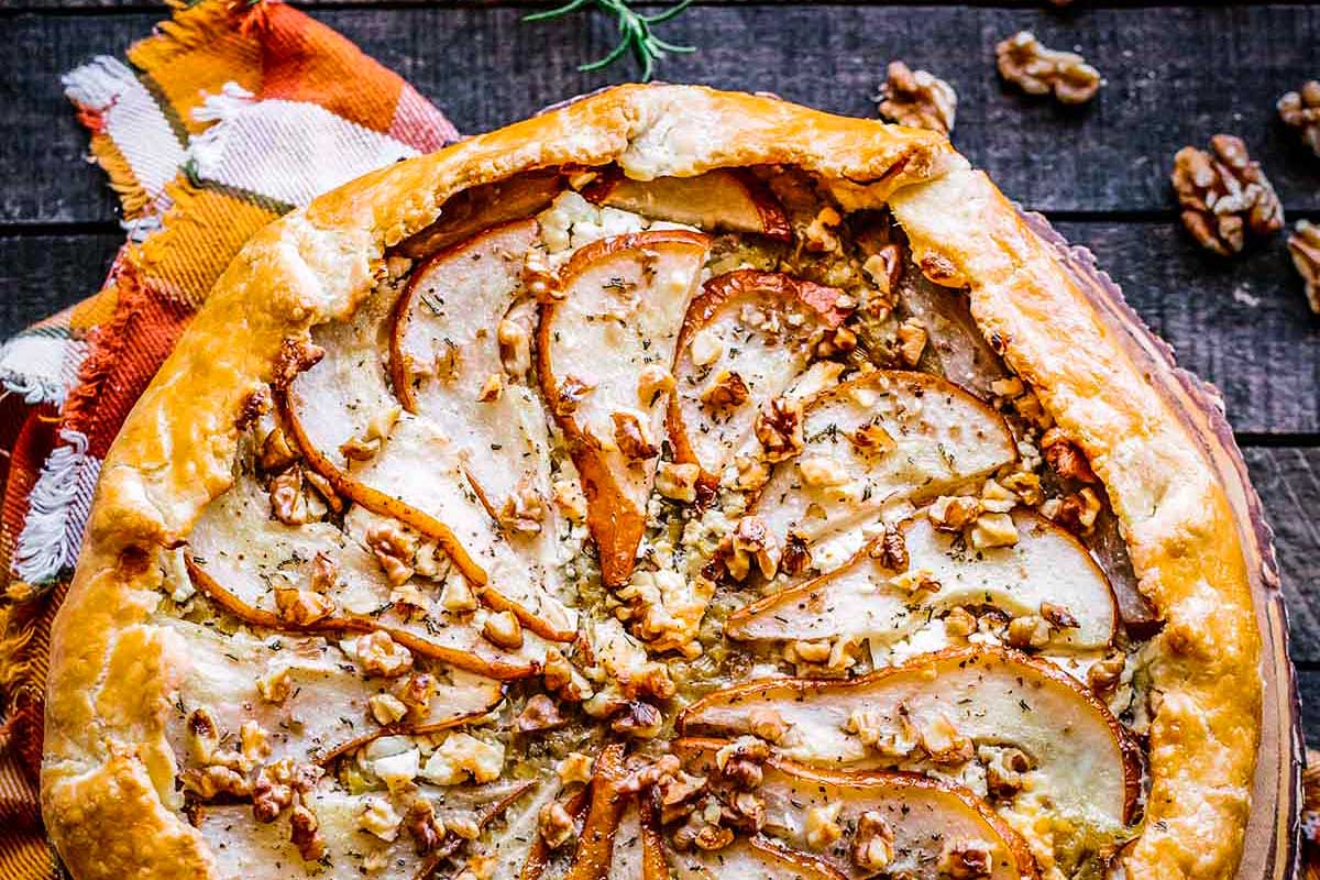 A friends giving pie with pears and walnuts on top.