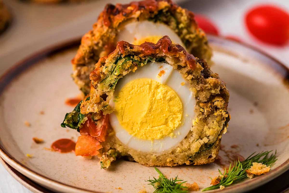 A delectable brunch recipe featuring a plate adorned with an egg stuffed with spinach and tomatoes.