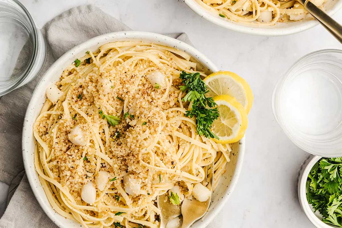 A romantic bowl of pasta, sprinkled with parmesan cheese and garnished with parsley, perfect for a delightful date night.