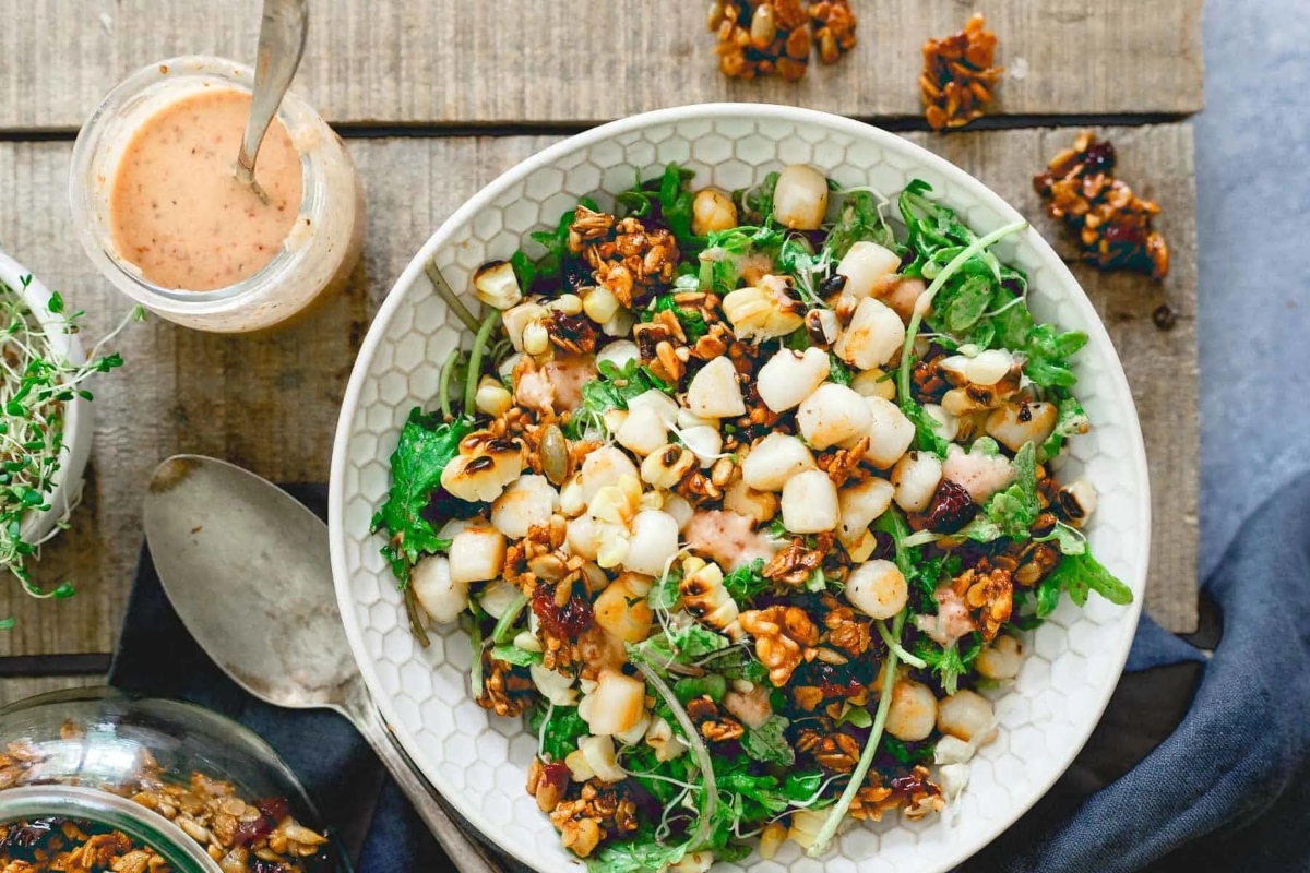 A bowl of salad with a dressing on it.
