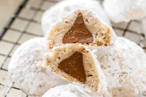 A stack of white powdered cookies with a bite taken out of them.