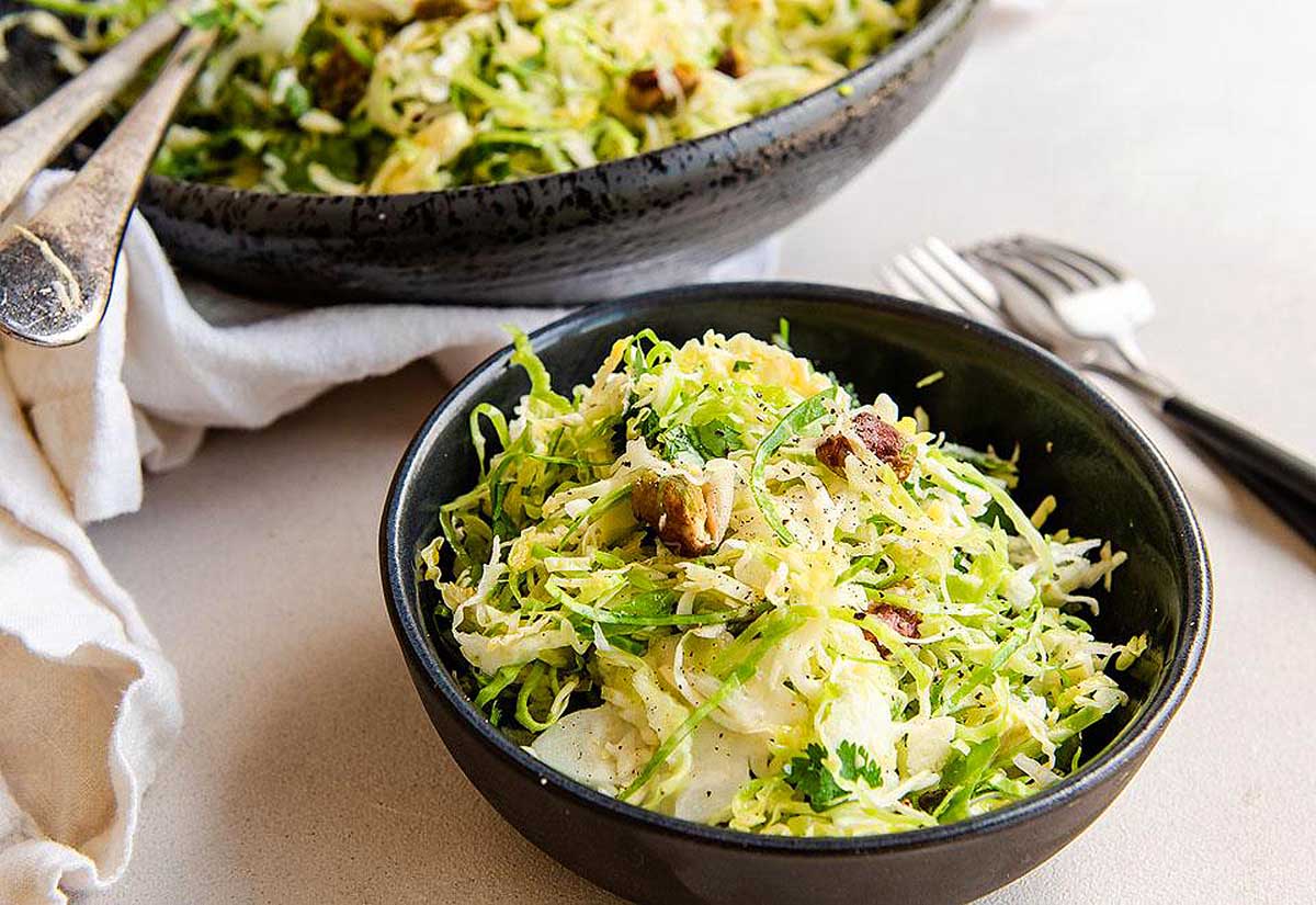 A bowl of brussels sprout salad with walnuts.