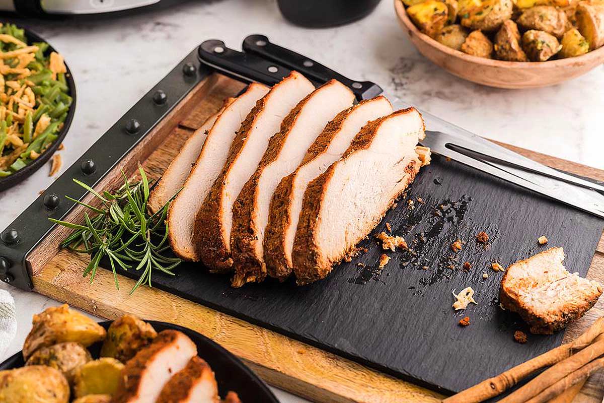 Sliced meat on a cutting board next to a slow cooker, perfect for friends giving.