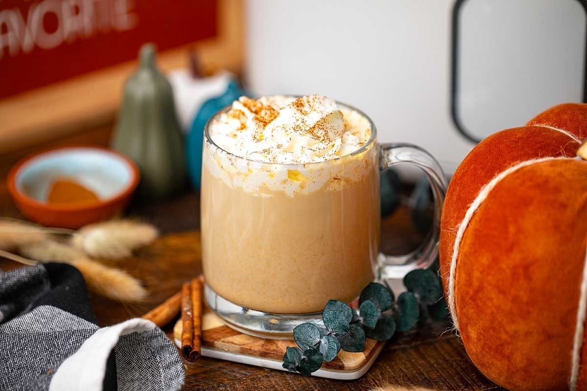 A holiday-themed pumpkin spice latte served on a wooden table at Starbucks.