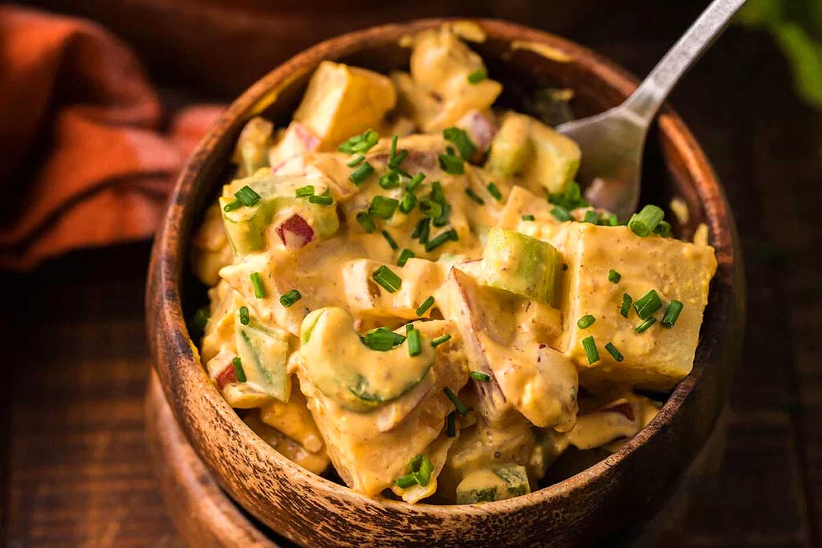 A bowl of chicken and avocado salad with a spoon.