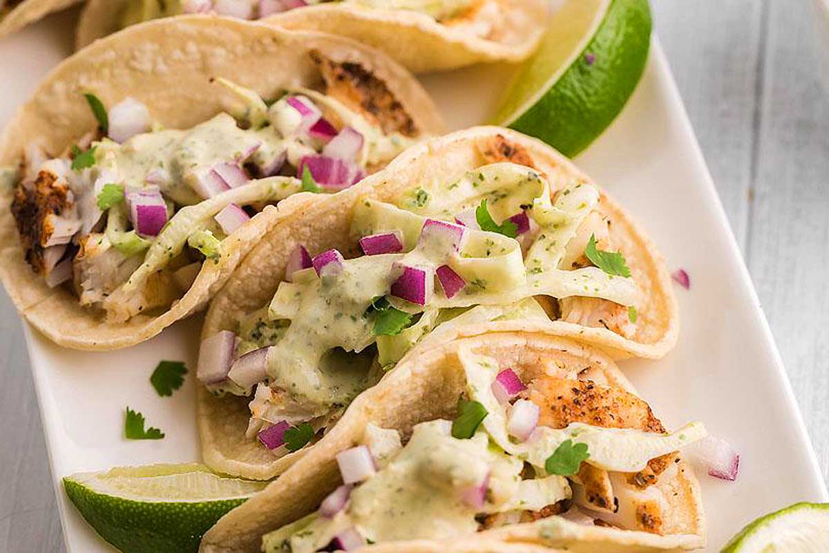 A plate of tacos with limes and meat.