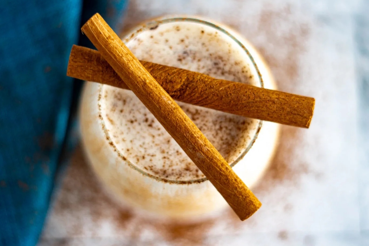 A festive eggnog drink garnished with cinnamon sticks on top.