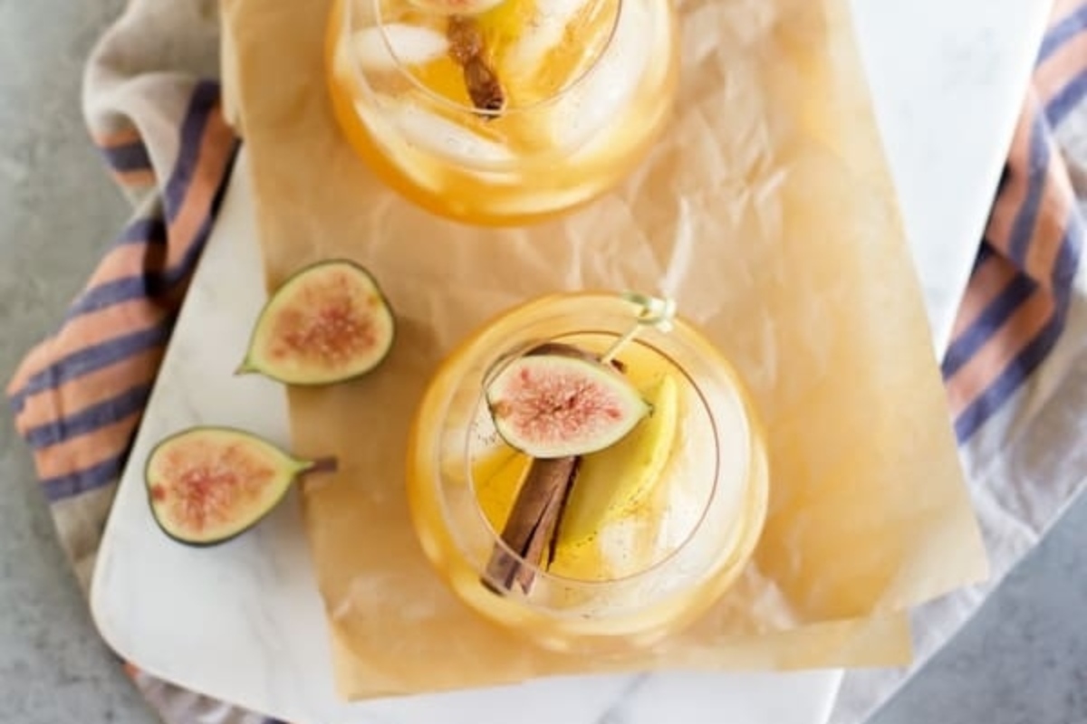 Thanksgiving cocktails featuring two glasses of sangria topped with figs and sprinkled with cinnamon.