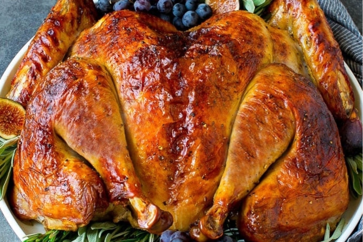 A Thanksgiving roasted turkey with figs and grapes on a platter.
