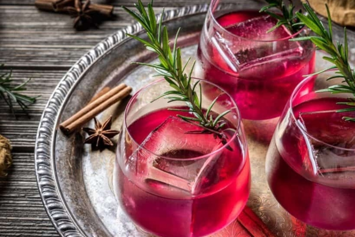 A glass of red wine infused with cinnamon sticks and rosemary sprigs, perfect for cozy evenings by the fire.