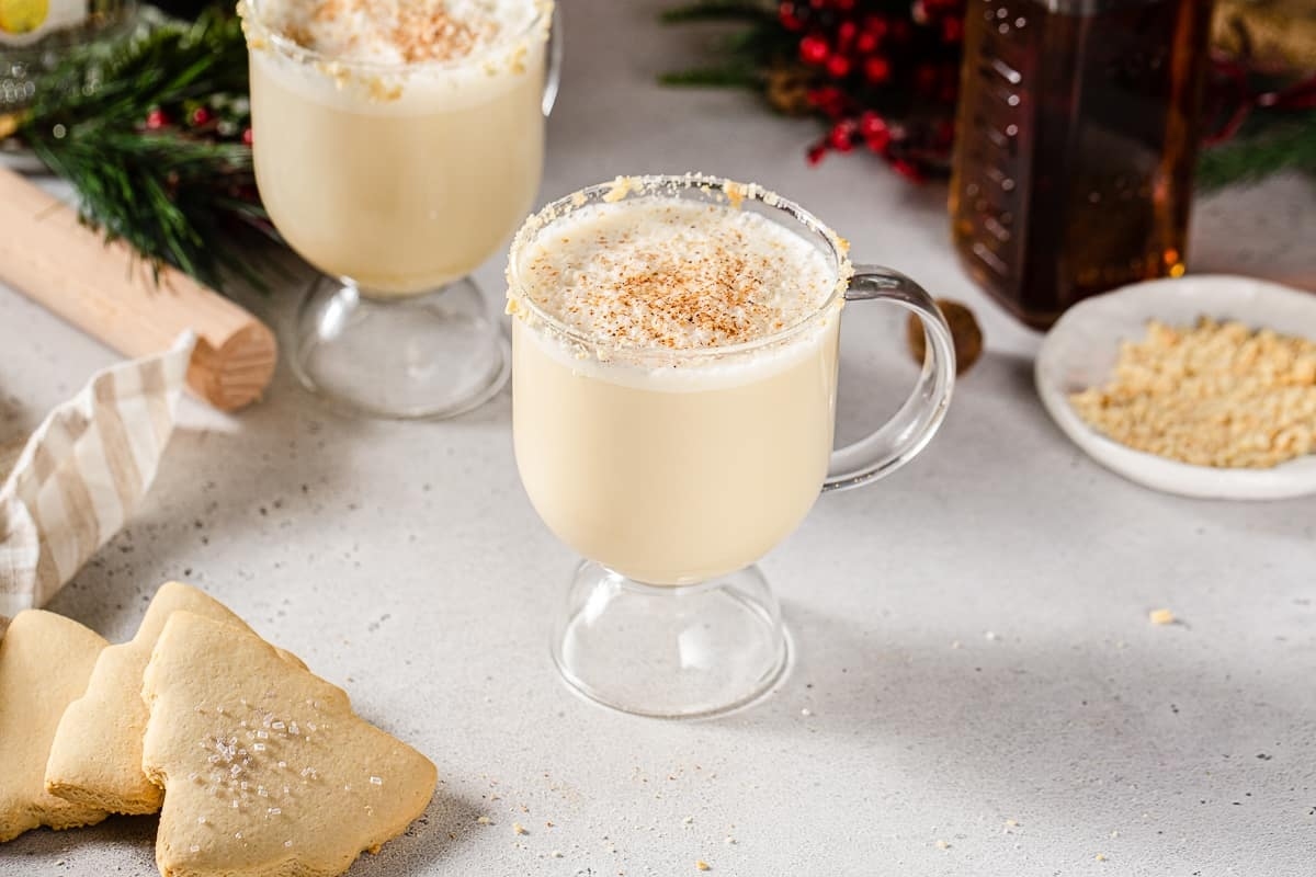 A cup of eggnog with gingerbread cookies on the side, perfect for holiday gatherings and cozy nights by the fire.