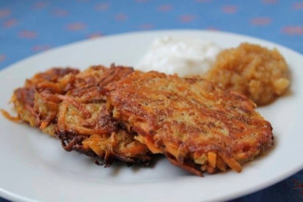 Carrot pancakes with sour cream on a plate.