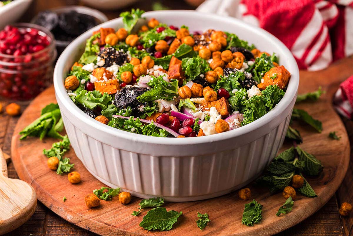 A salad with kale and sweet potato in a white bowl.