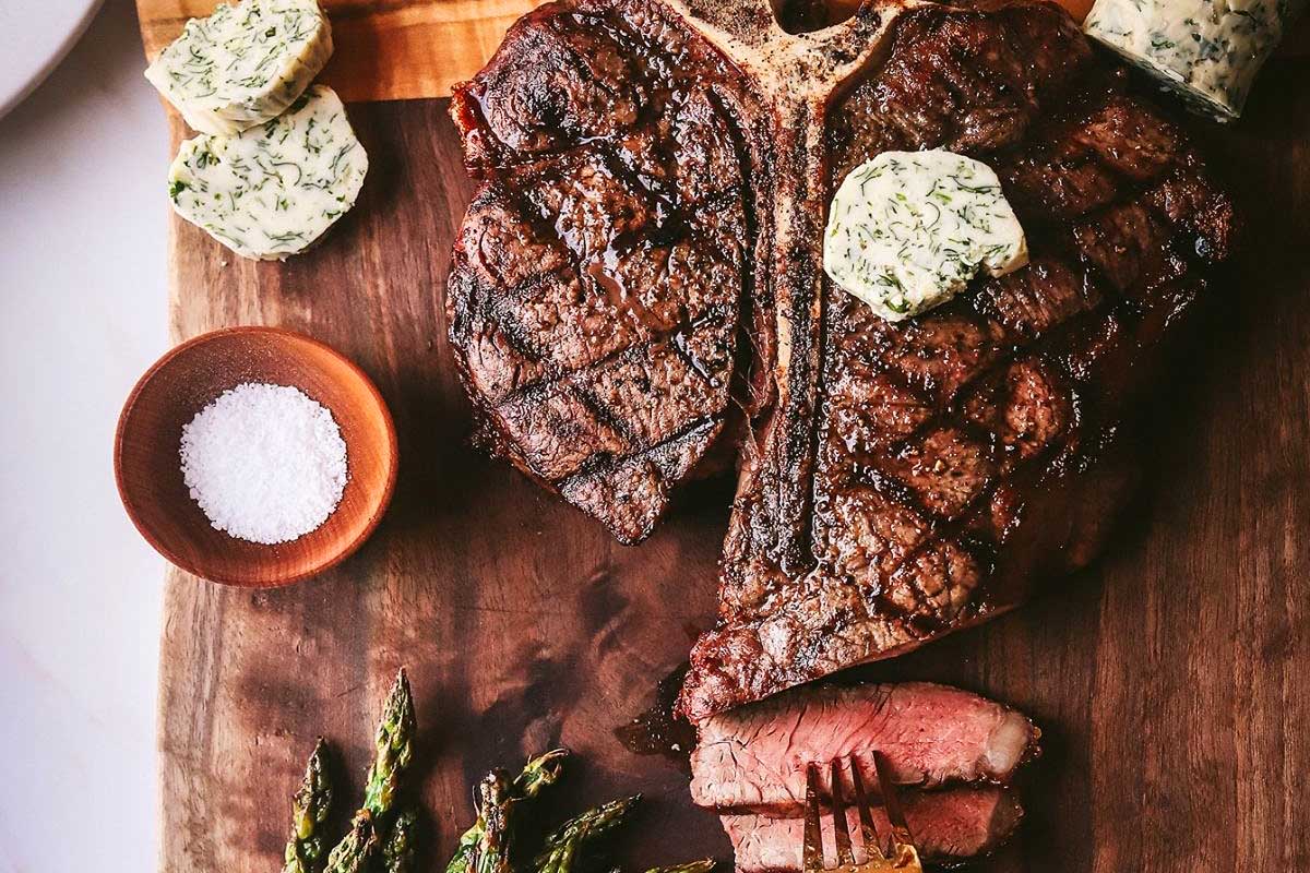 A steak on a cutting board with asparagus.