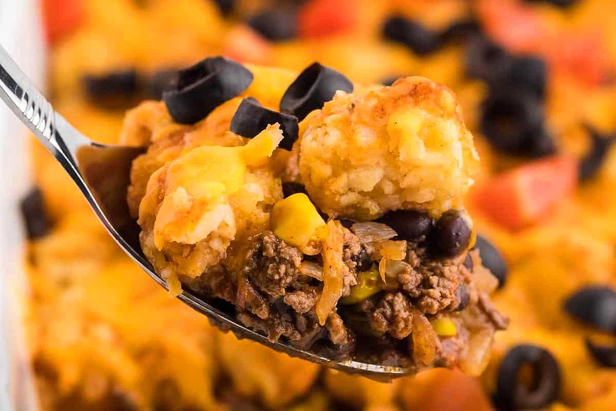 A spoonful of mexican casserole with black beans and black olives.