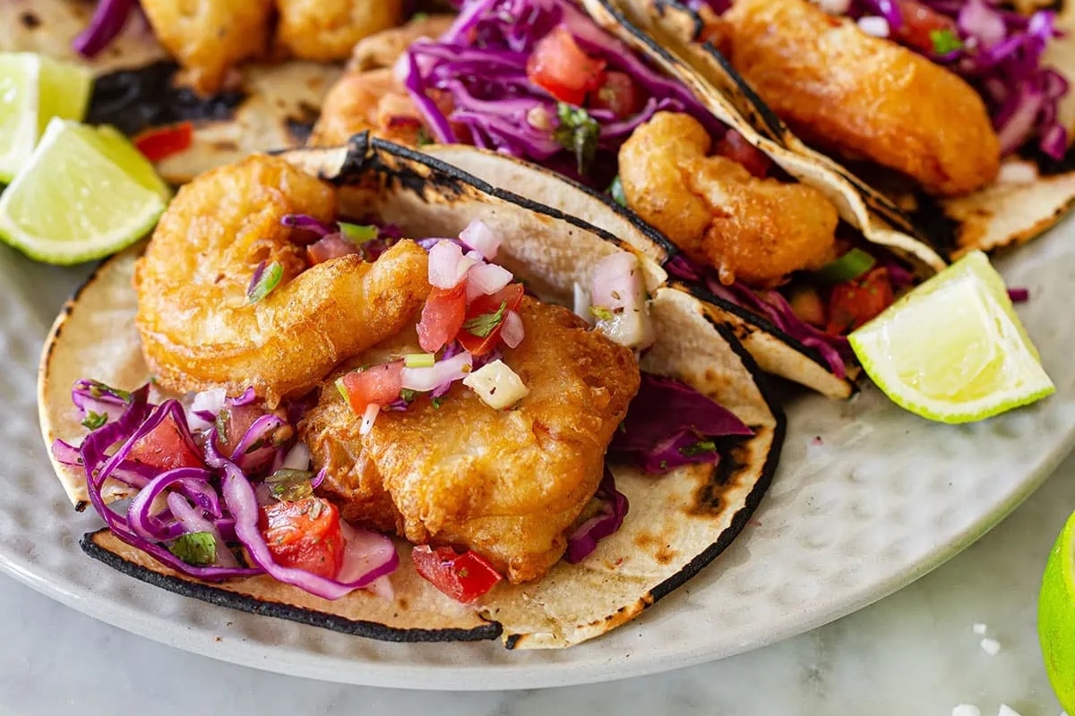 Fried fish tacos with slaw and lime wedges.