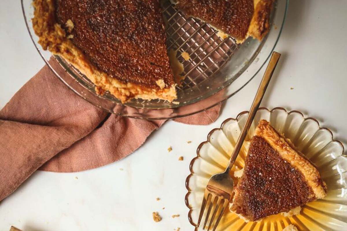 A slice of pumpkin pie on a plate garnished with a fork.
