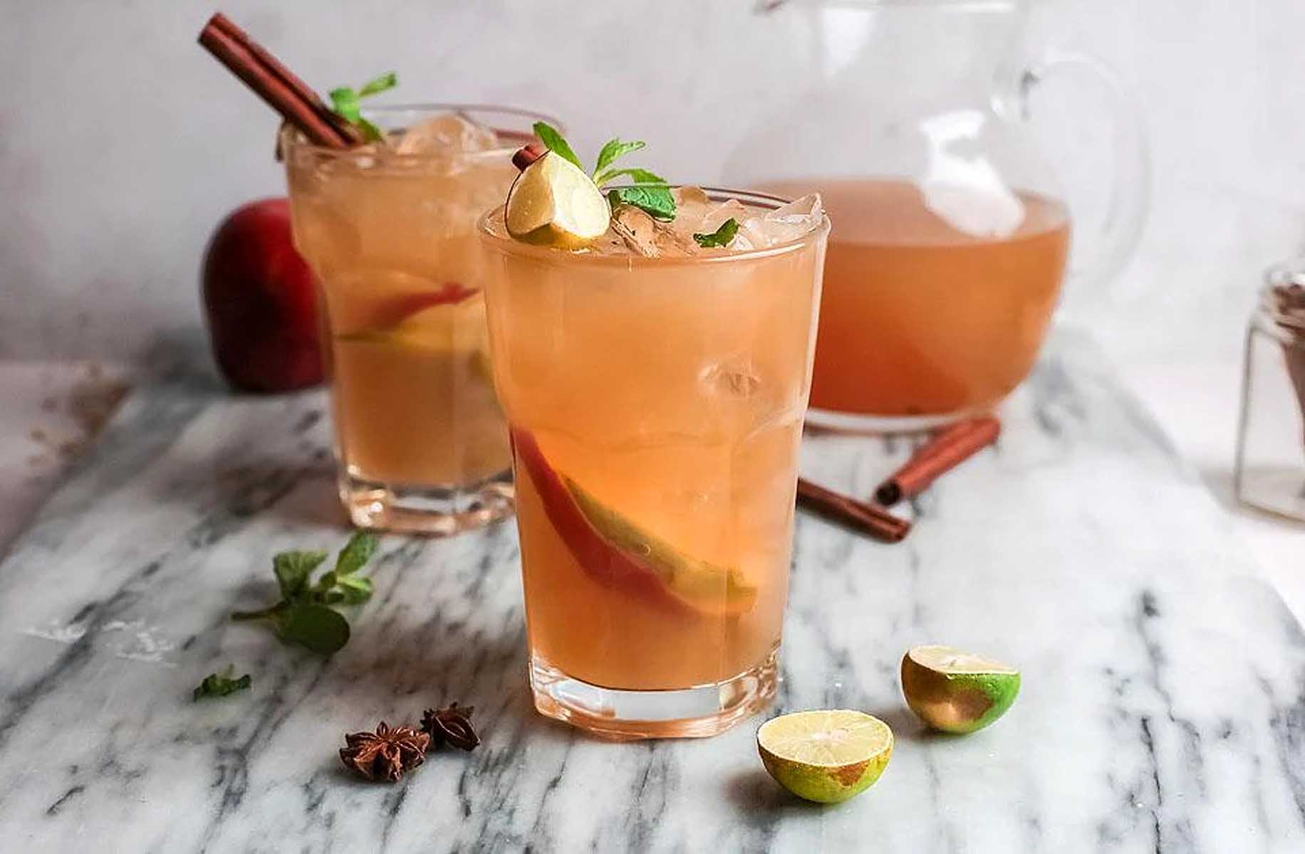 Two glasses of apple cider on a marble table.